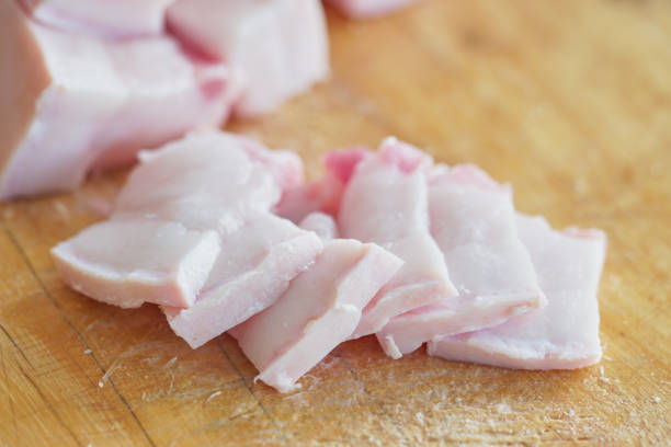 The pork is turned into small pieces placed on a wooden cutting board.