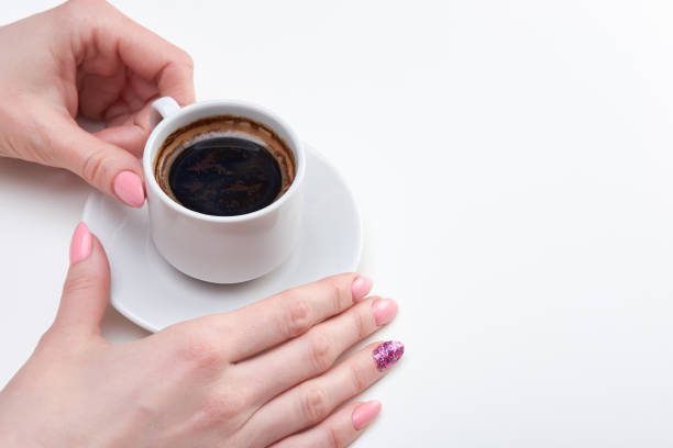 istock Woman's hands holding cup of espresso, white background 1136571064