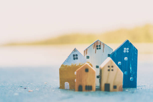 istock Closed up tiny home models on sand with sunlight and beach background. 1136573383