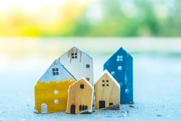 istock Closed up tiny home models on sand with sunlight and beach background. 1136573397