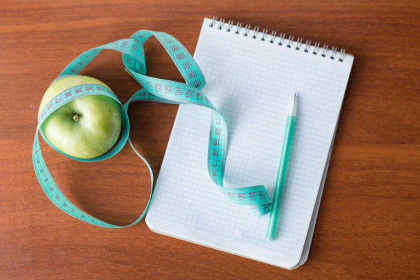 istock apple and a notebook on a wooden background.Diet concept. health 1136575403