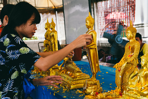 Bangkok, Thailand - April 13, 2018 Thai people on a traditional buddhist ceremony pouring Buddha statues at What Arun during Songkran
