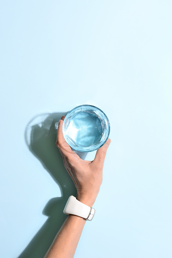 Woman's hand holding a glass of water, minimalist concept, view from above, blank space for a text
