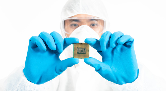 Electronic Manufacturing Factory Design Engineer in Sterile Coverall Holds Microchip with Gloves and Examines it , nano technology concept