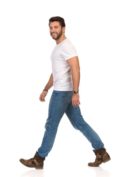 istock Smiling Walking Man In White T-shirt, Jeans And Boots Is Looking At Camera 1136585172