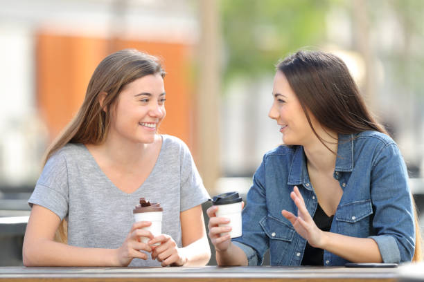 istock Two friends talking and drinking in a park 1136590037
