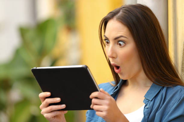istock Surprised woman checking content on tablet outdoors 1136590104