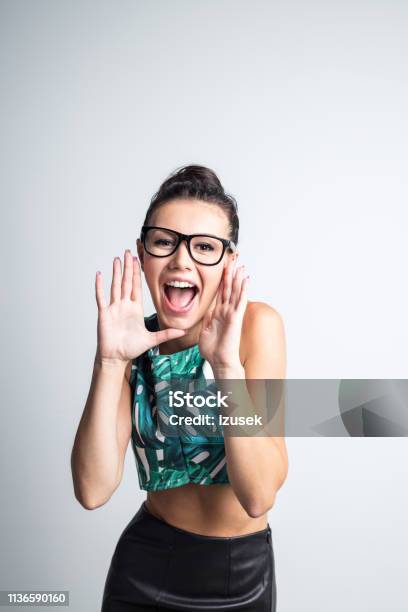 Excited Young Woman Shouting Stock Photo - Download Image Now - Announcement Message, Eyeglasses, One Woman Only