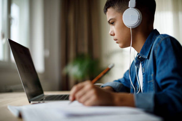 istock Teenage boy listening to music while doing homework 1136595023