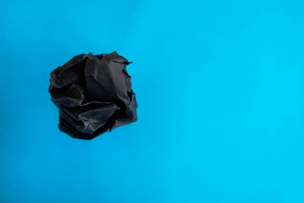 istock Black Crumpled paper ball on blue background. 1136595253