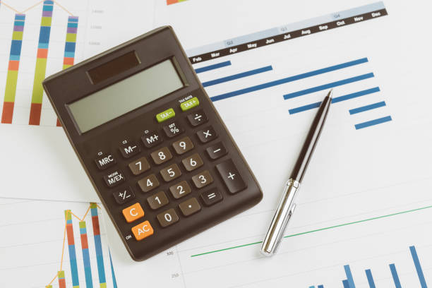 istock Black calculator, pen on monthly graph and chart on office table using as company profit and loss, financial and accounting activities 1136595323
