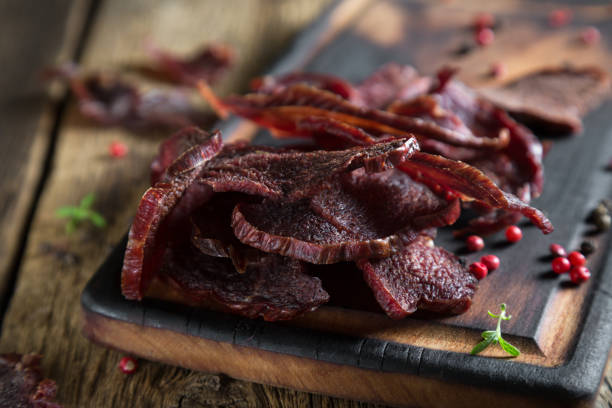 beef jerky on a rustic wooden table - beef jerky meat smoked imagens e fotografias de stock