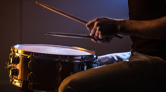 man playing the snare drum on a beautiful colored background, the concept of musical instruments