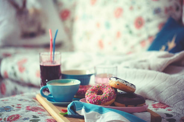 Colourful donuts, coffee and lemonade for a cozy TV afternoon in the living room on the couch