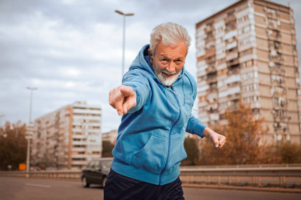 istock Senior man jogging on a city bridge pointing to camera 1136597043