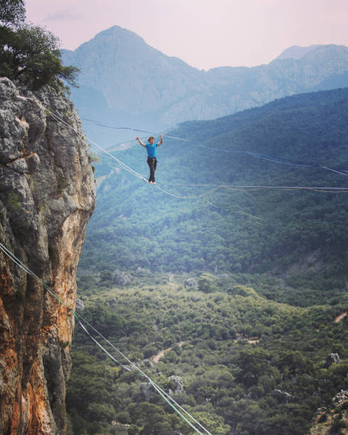 Man balancing on the rope concept of risk taking and challenge. Man balancing on the rope concept of risk taking and challenge. highlining stock pictures, royalty-free photos & images