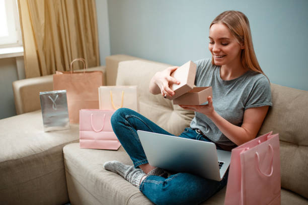 zakupy online w domu. młody uśmiechnięty kupujący rozpakowywanie jej paczki i patrząc, zamówione i dostarczone przez internet - box open merchandise gift zdjęcia i obrazy z banku zdjęć