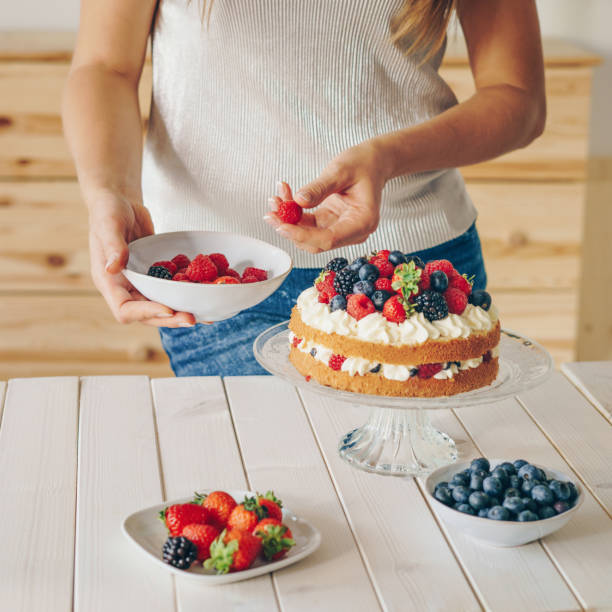 istock Woman decorating a cake with fresh berries 1136602528