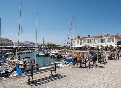 Isle of Re, France - August 6 2018 : the old harbor of Saint-Martin is the most picturesque of the Isle of Re with its historic houses turned into stores. Right in front of La Rochelle on the west coast of France, it is very popular in summer with its restaurants and shops close to the marina.