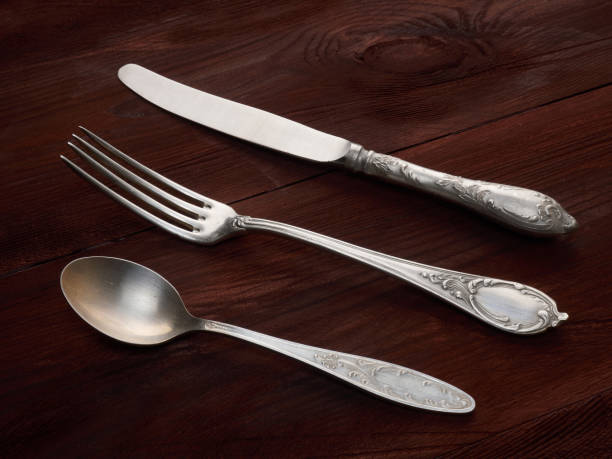 istock Cupronickel fork, knife, spoon on brown wooden background with copy space 1136606535