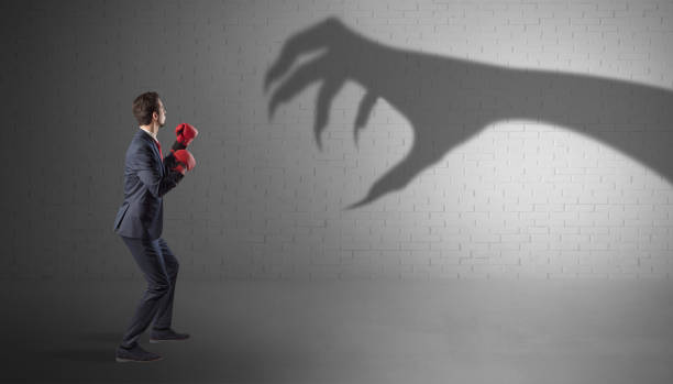 istock Businessman fighting with scary hand shadow 1136607929