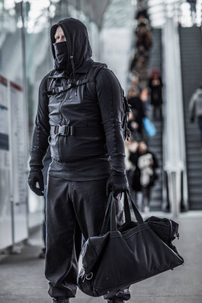 istock Dark hooded  figure in crowded urban surroundings 1136610326