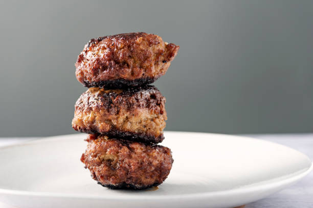 Stack of 3  Danish meat balls or frikadeller in Danish. They are a staple of the Danish diet and they are traditionally made from a mix of veal and pork, herbs and spices such as sage and thyme as well as salt and pepper. Colour, horizontal with some copy space.