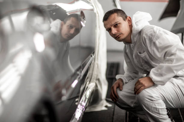 istock Car colorist looking at the door segment of the car at an angle while crouching 1136614611