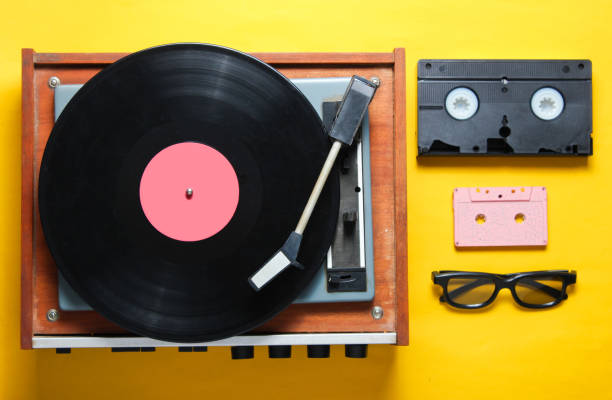 style rétro, des années 80, la culture pop attributs sur un fond jaune. lecteur de vinyle, lunettes 3d, audio, cassette vidéo. vue de dessus - digital video disk photos et images de collection