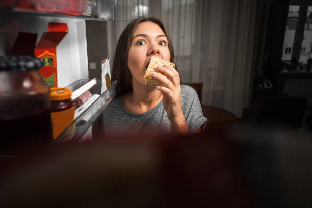 a mulher nova olha no refrigerador, vista do refrigerador, menina que come na noite, medos - healthy eating snack child domestic kitchen - fotografias e filmes do acervo