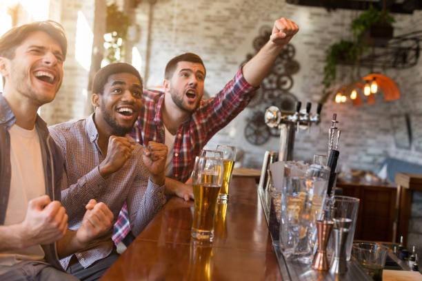 мужчины болеют за футбольную команду в спортивном баре - beer bar counter bar beer glass стоковые фото и изображения