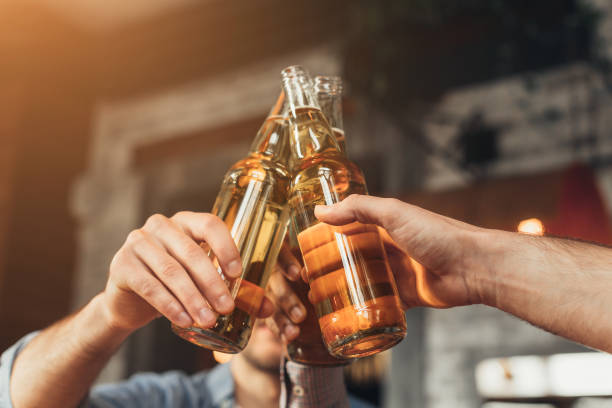hombres que reunen botellas de cerveza en bar - clunking fotografías e imágenes de stock