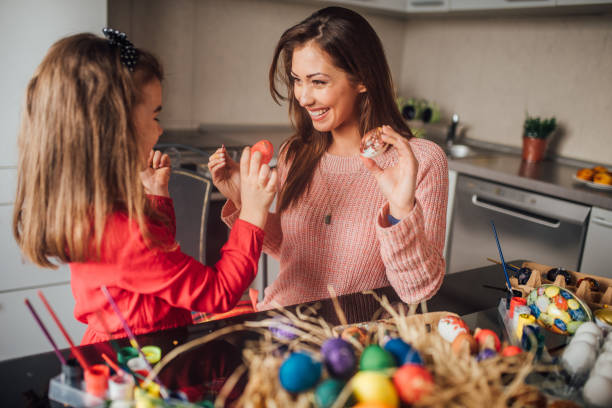 istock Woman decorating Easter eggs with family 1136617790