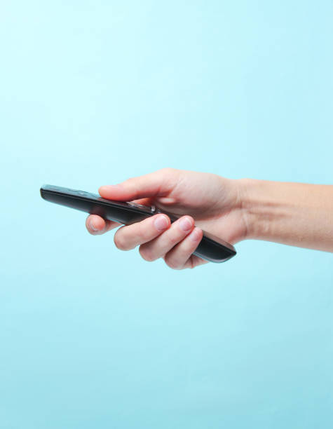 istock Hand holding tv remote on a blue background. Side view 1136618755