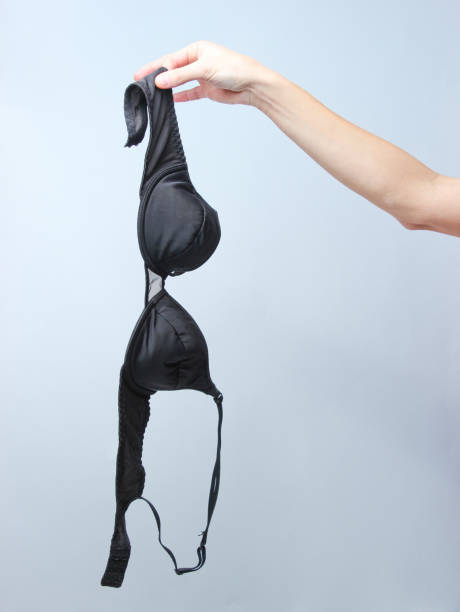 회색 배경에 검은 브래지어를 들고 여성 손. - undressing women panties stripper 뉴스 사진 이미지