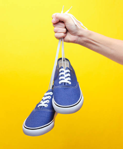 istock The hand holds by shoelaces retro style hipster sneakers 1136618916