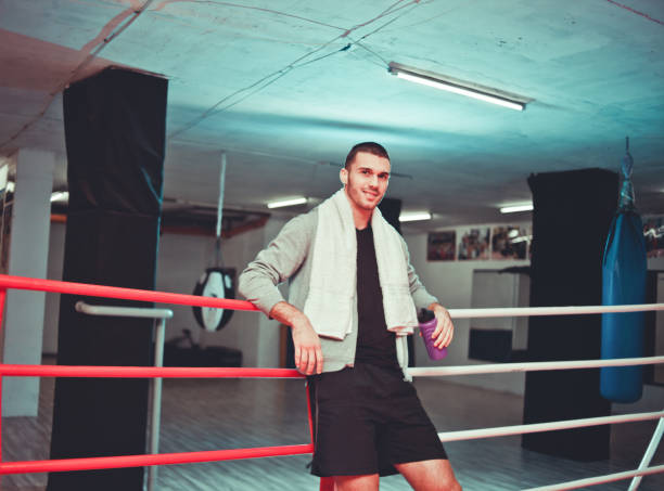 istock Rest boxer in the ring. Young boxer man with towel around his neck smiles while resting near the sides of the ring. 1136620672