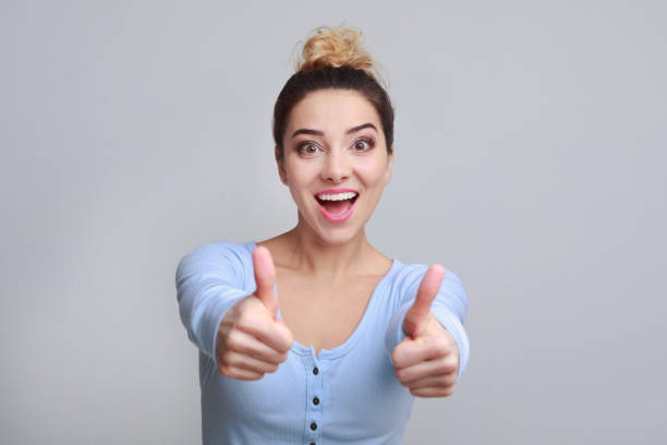 istock Excited woman showing thumbs up, grey background 1136621059