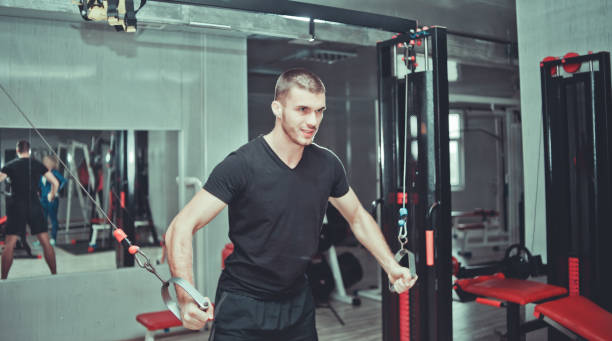 istock handsome sporty man works out pushing up excercise in crossover training machine at gym 1136621399