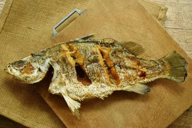 istock deep fried salty bass fish on wooden chop block 1136622852