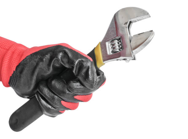 istock Adjustable wrench in a man's hand in a red working glove. Locksmith tool 1136624270