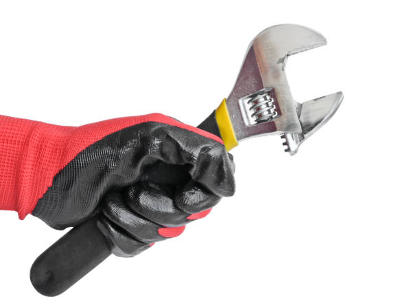 istock Adjustable wrench in a man's hand in a red working glove. Locksmith tool 1136624287