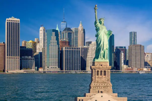 Photo of Statue of Liberty and New York City Skyline with Skyscrapers of Manhattan Financial District, NY, USA.