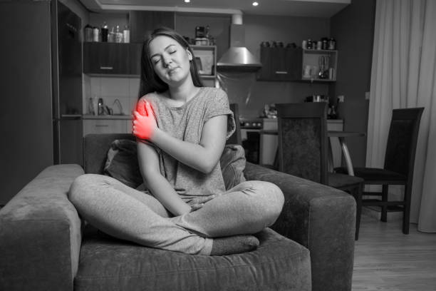 young woman has shoulder pain, black and white photo red accent - inflammation back physical therapy isolated on white imagens e fotografias de stock