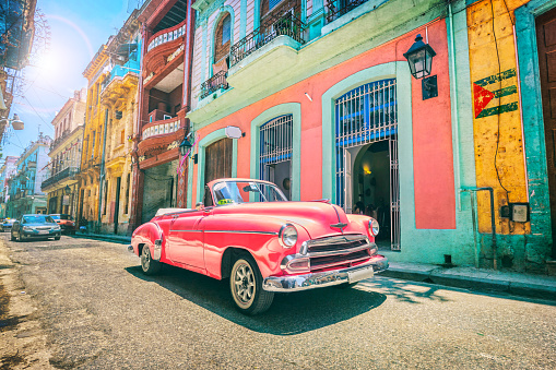 Coche viejo de color rosa Vintage conduciendo a través de la Habana Vieja Cuba photo