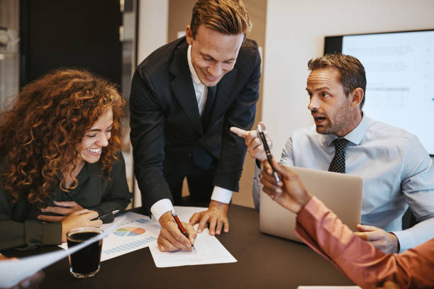 istock Smiling businesspeople talking together over paperwork in an office 1136628309