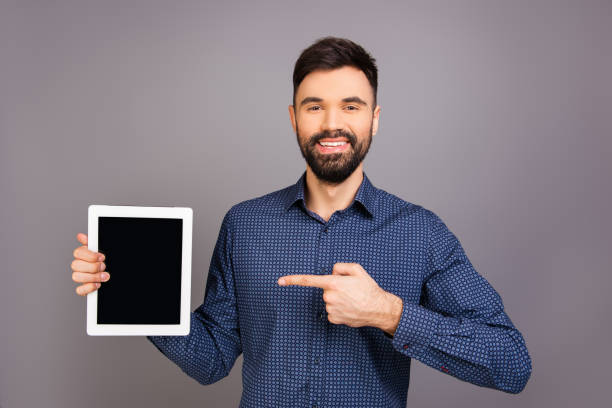 istock Handsome happy young businessman pointing on screen of tablet 1136628338