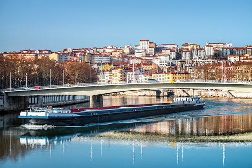 Color photography of Lyon city buildings from Croix Rousse district with famous red rooftop, french culture architecture and wonderful ancient monuments, seen from Saone river point of view in early sprnig season. Image taken from public area outdoors, along riverbank. This photo was taken in Lyon city, Unesco World Heritage Site, in Rhone department in Auvergne-Rhone-Alpes region, in France (Europe) in february, during a bright sunny day.