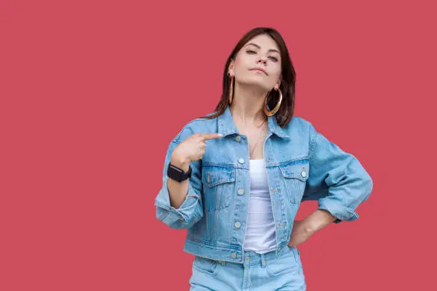 Photo of Portrait of proud beautiful brunette young woman with makeup in denim casual style standing, pointing herself and looking at camera with haughty face.