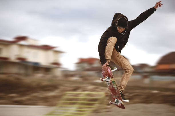 Close up of a skateboarders feet while skating active performance of stunt teenager shot in the air on a skateboard in a skate park stock photo